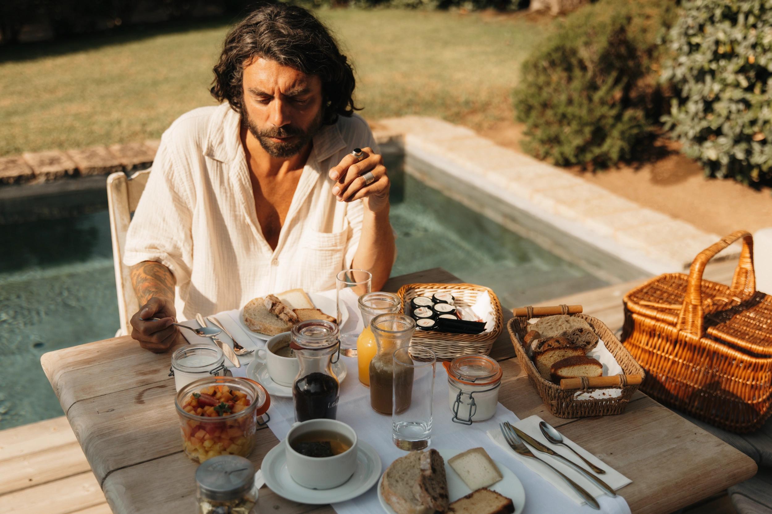Homme qui prend un petit déjeuner à côté d'une piscine aux Oliviers de Palombaggia en Corse-du-Sud.